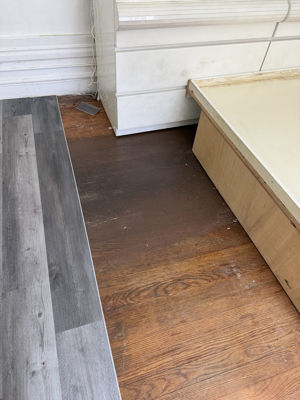 Gray planks beside an area of exposed existing flooring