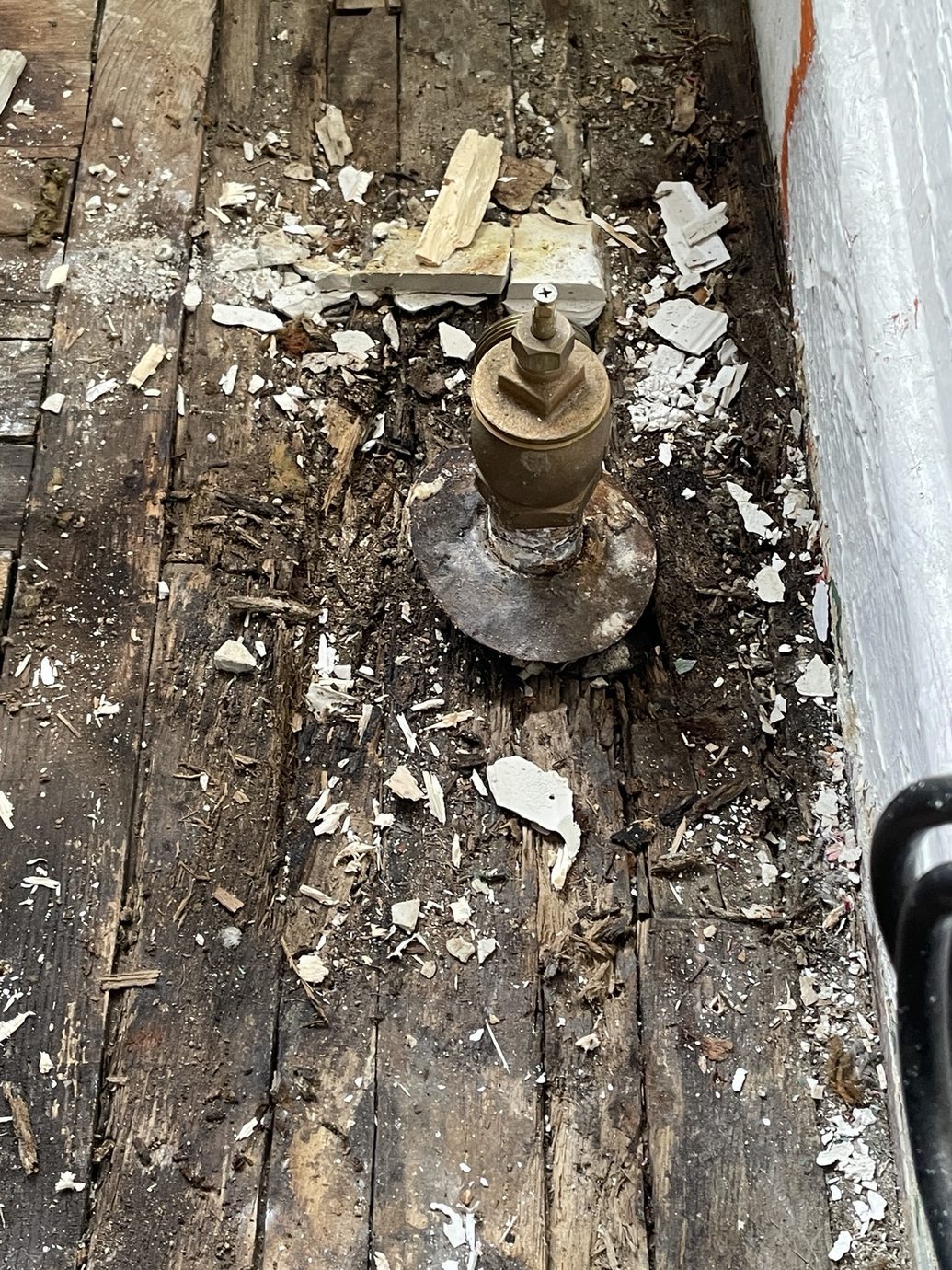 Opened wooden floor near a pipe and wall